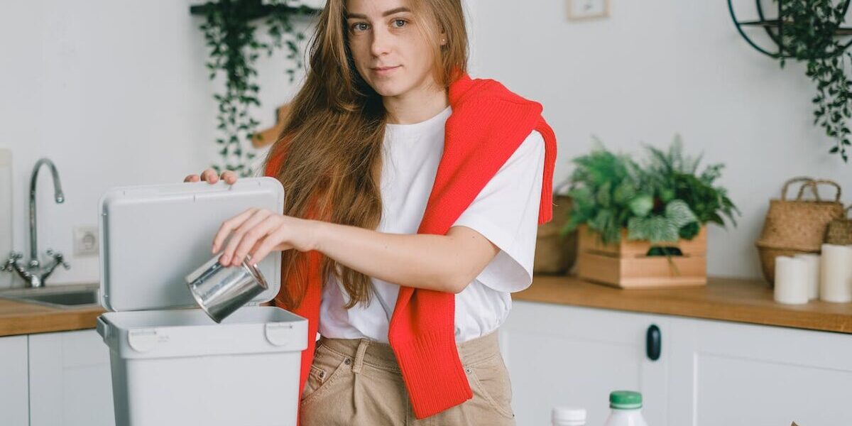 person putting the metal can into a trash can